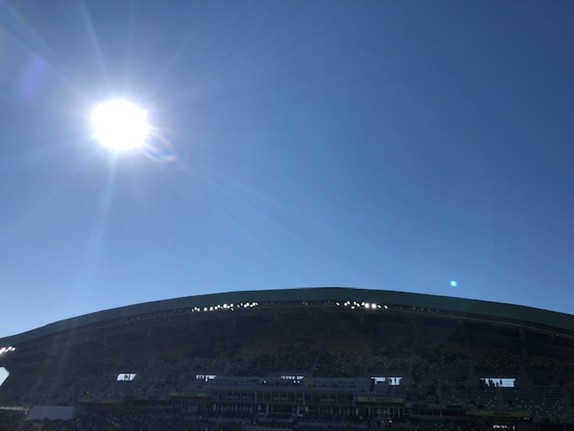 Sonne an blauem Himmel über einem Fussballstadion